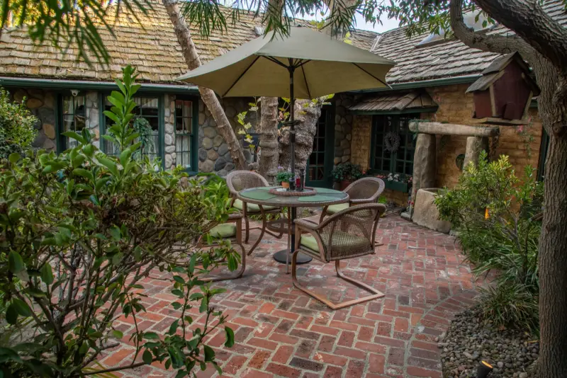 A brick courtyard with a dining table beside the cottage at The Enchanted Manor