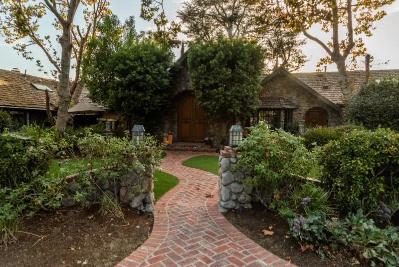 The brick path winding through the front gardens to the stone cottages at The Enchanted Manor