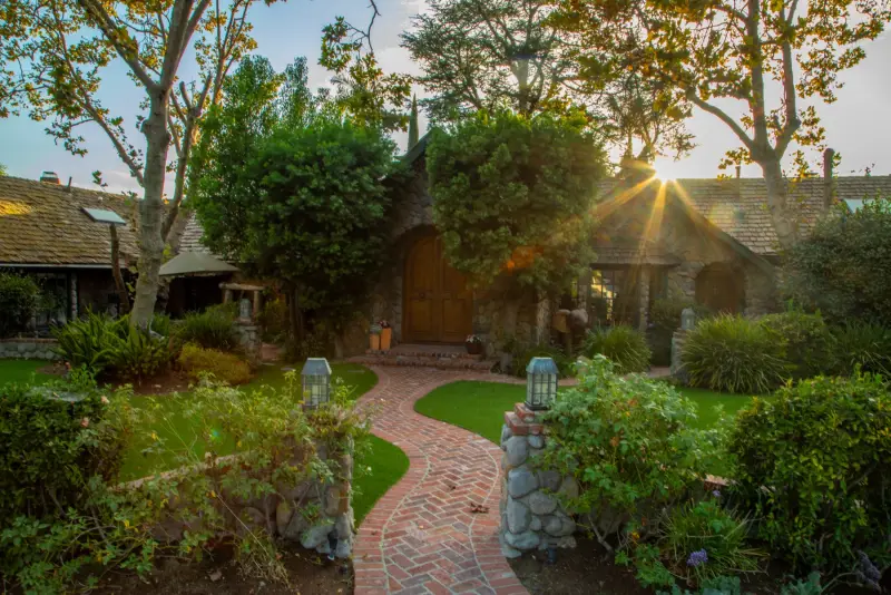 Late sun through the trees over the front path and cottages at The Enchanted Manor