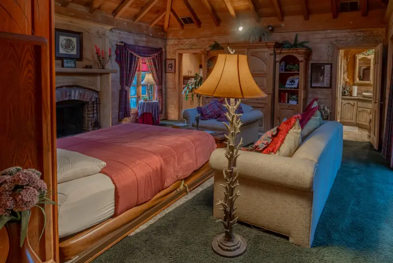The Inn's living room with fireplace and pulled-down queen bed at The Enchanted Manor