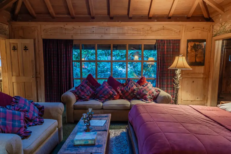 The Inn living room with plaid cushions and garden windows at The Enchanted Manor