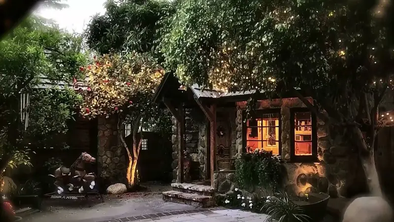 The stone cottage glowing through the trees at night at The Enchanted Manor