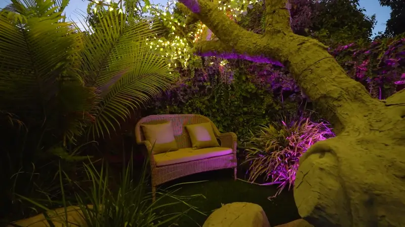 A garden seat under the lit tree, washed in violet light at The Enchanted Manor